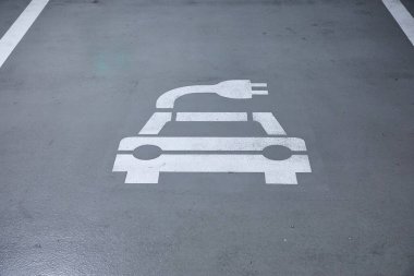 Bir yeraltı otoparkında elektrikli araba şarj istasyonu tabelası, elektrikli araç şarj aleti, uygun yuvaları.