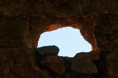 Karanlık kayalık mağara, açık bir penceresi var. Dışarıdaki parlak mavi gökyüzü ışığına bakıyor. Çukurun içindeki derin karanlıktan.