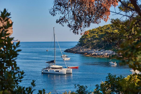 Summer holiday sail boat in a calm bay with rocky shore beach on Lokrum Island, Dubrovnik, Croatia. Vacation on the sunny Mediterranean Sea