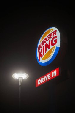 Budapeşte, Macaristan - 27 Ocak 2025: Burger King, yol kenarındaki bir direğin tepesinde, karanlıkta durmadan parlayan bir tabela imzaladı
