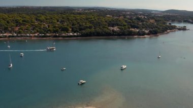 Hırvatistan 'ın Pula kentinin Uvala kenti yakınlarındaki Akdeniz kıyısındaki bir körfezin havadan görüntüsü. Yazın tekne gezintisi, güneşli hava, İHA görüntüleri.