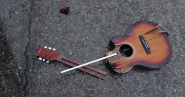 Karlı yağmurda yere düşen kırık bir gitar. Öfke, sokak çaldıktan sonra bırakıldı