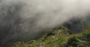 Bulutlar hızla geçiyor güçlü fırtınalı rüzgarda yüksek bir dağın zirvesinde, rüzgarda çimenler