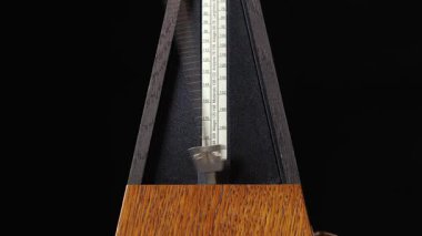 Klasik metronom tıklama, tik tak, siyah arkaplan, yakın plan, yavaş tempo, tekrarlanabilir video, düzenli aralıkları işaretleme, hızlı tempo