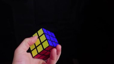 Budapeşte, Macaristan - 24 Ocak 2020: Rubiks 'in insan eliyle çözülmüş durumda tutulan, havaya atılan ve savrulan karanlık arka plan hakkındaki mantık oyunu