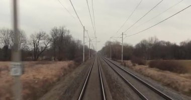 Tren yolculuğu bakış açısı son vagonun arkasından, demiryolu raylarından, yüksek hızda bir istasyondan geçen diğer tren bitişikteki raydan geçiyor.