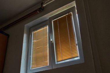 Bir apartmanın penceresi açık, içeri temiz hava giriyor, güneş ışığını engelliyor.