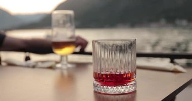 Plaj restoranında içki içmek, Negroni kokteyli ve masada bir bardak bira içmek.