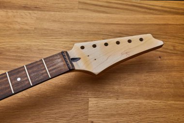 Elektro gitar atölyesi, boyun ve başlık, çıplak ahşap yüzey, telsiz ve akortsuz.