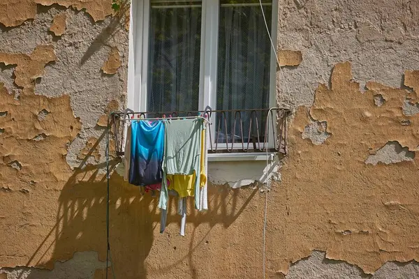 Çamaşır ipinde kurumuş giysiler şehir balkonunun camında.