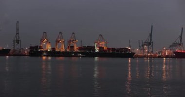 Gece Rotterdam limanındaki kargo konteynırı nakliye terminalinde limanda büyük konteynır gemileri limanda vinçlerle yüklendi.