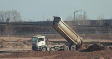 Budapeşte, Macaristan - 10 Şubat 2022: Tozlu bir yol inşaatında çöp kamyonu, ağır bir taşıma aracı toprak yığını içine boşaltıyor