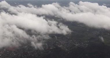 Bulutların üzerinde uçarken bulutların üstünde, uçağın penceresinden arazi manzarası, aşağıdaki yerleşim yerleri
