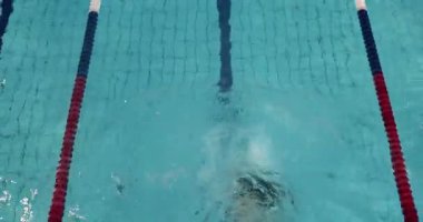 Kapalı yüzme havuzunda yüzen kadın serbest stil vuruşu, yüzey altından geçerken suyun altından geçen adam.