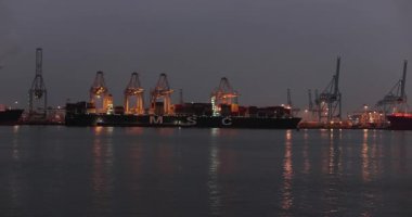 Rotterdam, Hollanda - 12 Şubat 2023: Kargo konteynır nakliye terminali gece Rotterdam limanında, Maasvlakte limanında gantry vinçlerle dolu büyük bir konteyner gemisi