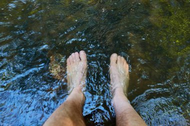 Serin bir dağ deresinde çıplak ayaklar yaz yürüyüşü için dinleniyor.
