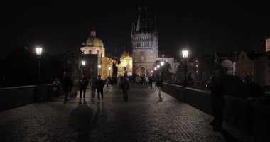 Prag, Çek Cumhuriyeti - 18 Ekim 2023: Prag 'ın tarihi kent merkezinde Charles Köprüsü' nde gece yürüyüşü, ünlü tarihi kent merkezinden geçen turistler