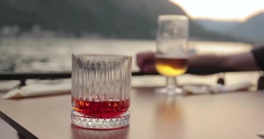 Deniz kenarındaki bir restoranda içki içmek, Negroni kokteyli ve masada bir bardak bira içmek..