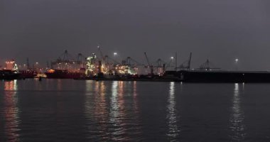 Gece Rotterdam limanındaki kargo konteynırı nakliye terminalinde limanda büyük konteynır gemileri limanda vinçlerle yüklendi.
