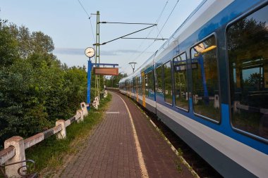 Macaristan 'ın Ecser kasabasındaki küçük bir tren istasyonunda elektrikli yolcu treni.