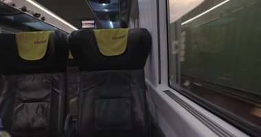 Pardubice, Çek Cumhuriyeti - 2 Haziran 2025: Çek özel demiryolu şirketi Regiojet ile gün batımında seyahat eden tren yolculuğu penceresi manzarası ve ücretsiz koltuklar. Konteyner yük treni geçiyor.