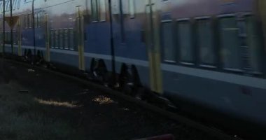 Ecser, Hungary - December 27, 2023: Electric passenger train at a small railway crossing passing by without stopping. Stadler KISS double decker multiple unit