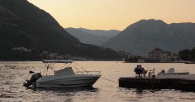 Kotor, Montenegro - July 26, 2024: Seaside bay view with boats on Mediterranean coast, rippling water surface at a pier, Kotor bay surrounded by mountains