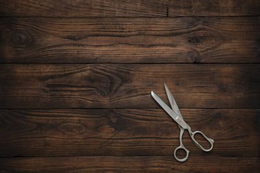 Koyu ahşap masada terzi makası. Uzayı metin için kopyala. Üst görünüm.