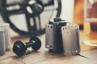 Fotoğraf ruloları ve kasetler, fotoğraf ekipmanları - film makaraları ve arka planda kimyasal reaktörleri olan geliştirme tankı.