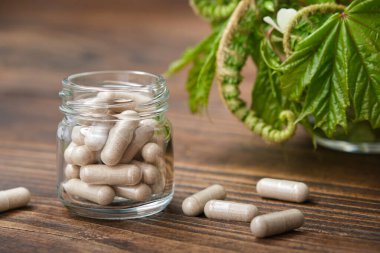 Bitkisel haplar, bir kavanoz doğal hap. Arka planda şifalı bitkiler.