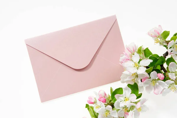 粉红信封 用结婚请柬或生日信装饰 用苹果树枝条装饰 平躺在床上顶部视图 — 图库照片