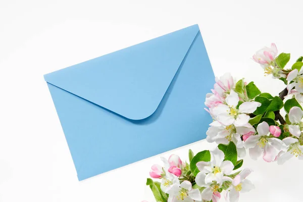 蓝色信封 装有结婚请柬或生日信 上面装饰着开花苹果树的枝条 平躺在床上顶部视图 — 图库照片