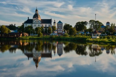 Akşamları eski Corpus Christi Kilisesi, Nesvizh, Minsk bölgesi, Belarus. Beyaz Rusya 'nın Nesvizh şehrindeki gölde yansıması olan uzak bir Tanrı' nın Vücut Tapınağı..