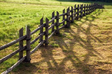 Güneşli bir yaz gününde bir damla gölgesi olan tahta çitler. Kırsal çit.