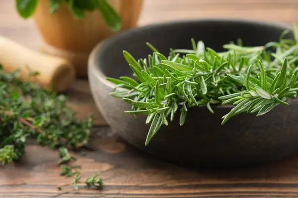 Bowl of fresh rosemary medicinal herbs. Twigs of thyme and mint on background. Healing herbs, Healthy cooking seasonings. Alternative medicine and healthy food.