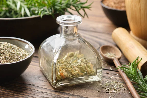Bottle of dry herbs for making healing infusion or tincture. Bowls of medicinal plants and wooden mortar on background. Alternative herbal medicine.