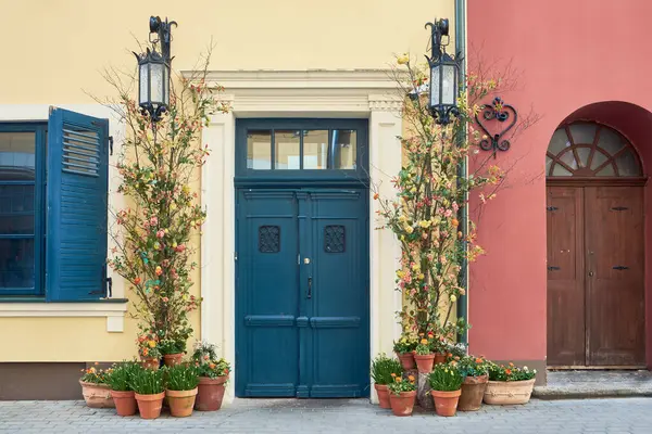 旧楼正面装饰着鲜花和盆栽中的春花的老式前门 图库照片