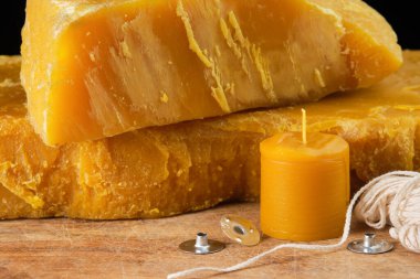 Doğal balmumu blokları, ahşap bir yüzeyde sergilenen mumlar için el yapımı mum, fitil ve metal fitil destekleyiciler..