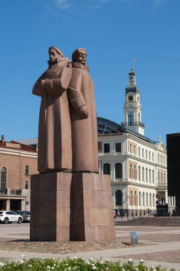 Riga, Letonya - 31-Temmuz-2024: Letonya Riga, Letonya 'daki Tüfek Adamları Anıtı. Sovyet döneminden kalma granit heykel, ağır paltolu iki tarihi figürü tasvir ediyor. Sırt sırta bir kaide üzerinde duruyor..  