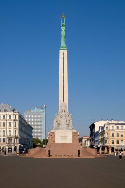 Letonya Riga 'daki Özgürlük Anıtı, açık mavi gökyüzüne karşı dimdik ayakta duruyor, Letonya bağımsızlığını ve ulusal birliği simgeliyor.