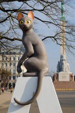 Letonya animasyon filmi Flow 'dan Cat RIGA tabelasında Oscar ve arka planda Özgürlük Anıtı, Riga, Letonya.