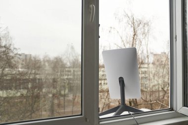 KYIV, UKRAINE - 8 JANUARY 2023: Starlink antenna for providing satellite internet access installed in window of high rise building. Real using of the terminal in the city