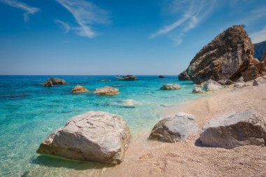 Akdeniz 'in mavi sularında büyük kayalar Cala Mariolu kumsalında Golfo di Orosei körfezinde güzel bir yaz günü İtalya' nın Sardegna sahilinde.