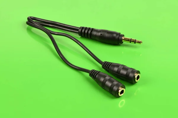 Audio cable splitter, stereo male to two female stereo audio jack 3,5 mm, isolated on a green background. Extreme closeup. High resolution photo. Full depth of field.