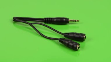 Ses kablosu ayırıcı, stereo erkek, yeşil arka planda iki kadın stereo ses düzenleyicisi 3,5 mm. Yan görüş. 4K UHD video görüntüsü 3840X2160.