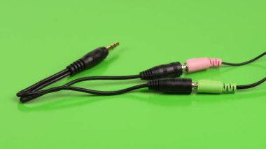 Ses kablosu ayırıcı, stereo erkek, yeşil arka planda iki kadın stereo ses düzenleyicisi 3,5 mm. Yan görüş. 4K UHD video görüntüsü 3840X2160.