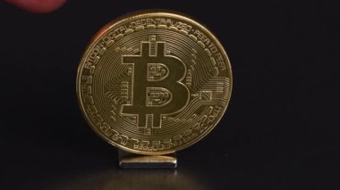 Kripto döviz kuru konsepti. Bitcoin siyah arka planda sallanırken yana doğru sallanır ve yavaş yavaş durur. Ön manzara. 4K UHD video görüntüsü 3840X2160.