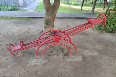 Evin yakınındaki avluda iki kişilik eski bir kırmızı salıncak. Sovyetler Birliği 'nde tipik bir vuruş..