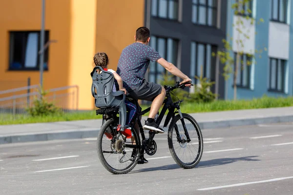 father riding bike with son in bike seat.