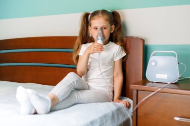 Girl making inhalation with nebulizer at home.